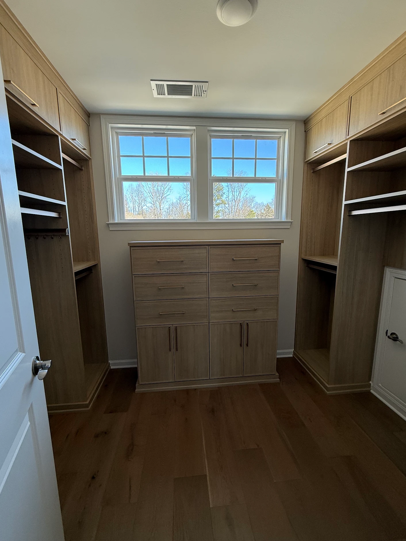 Custom walk-in closet project with wood-tone cabinetry and drawers